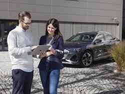 Ein Mann und eine Frau stehen auf einem Parkplatz und reden miteinander. Hinter ihnen parken zwei Autos.